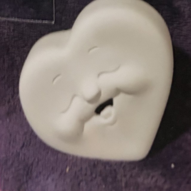 Heart face, left side, teeth, unpainted bisque, front view on black velvet